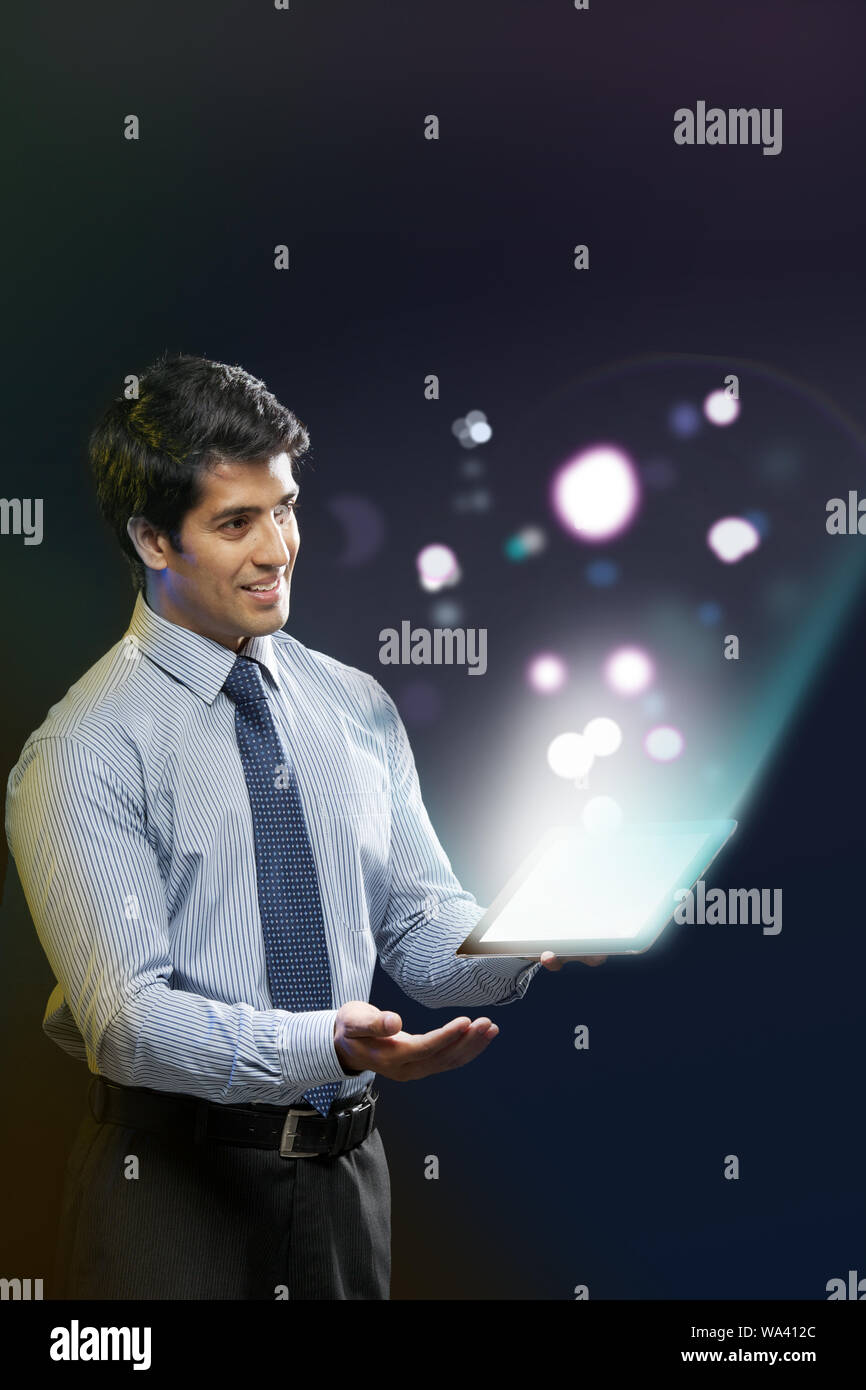 Businessman looking at lights coming from a digital tablet Stock Photo