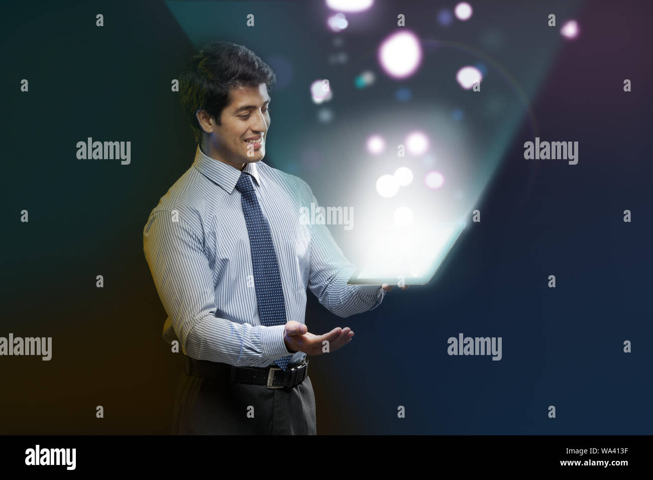 Businessman looking at lights coming from a digital tablet Stock Photo