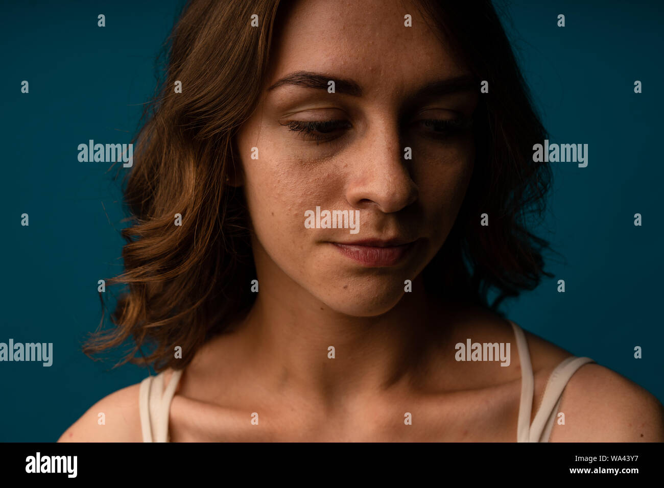 Stressed young woman confused about facial wrinkles aging skin on forehead or crows feet looking at camera isolated on studio background, upset worrie Stock Photo