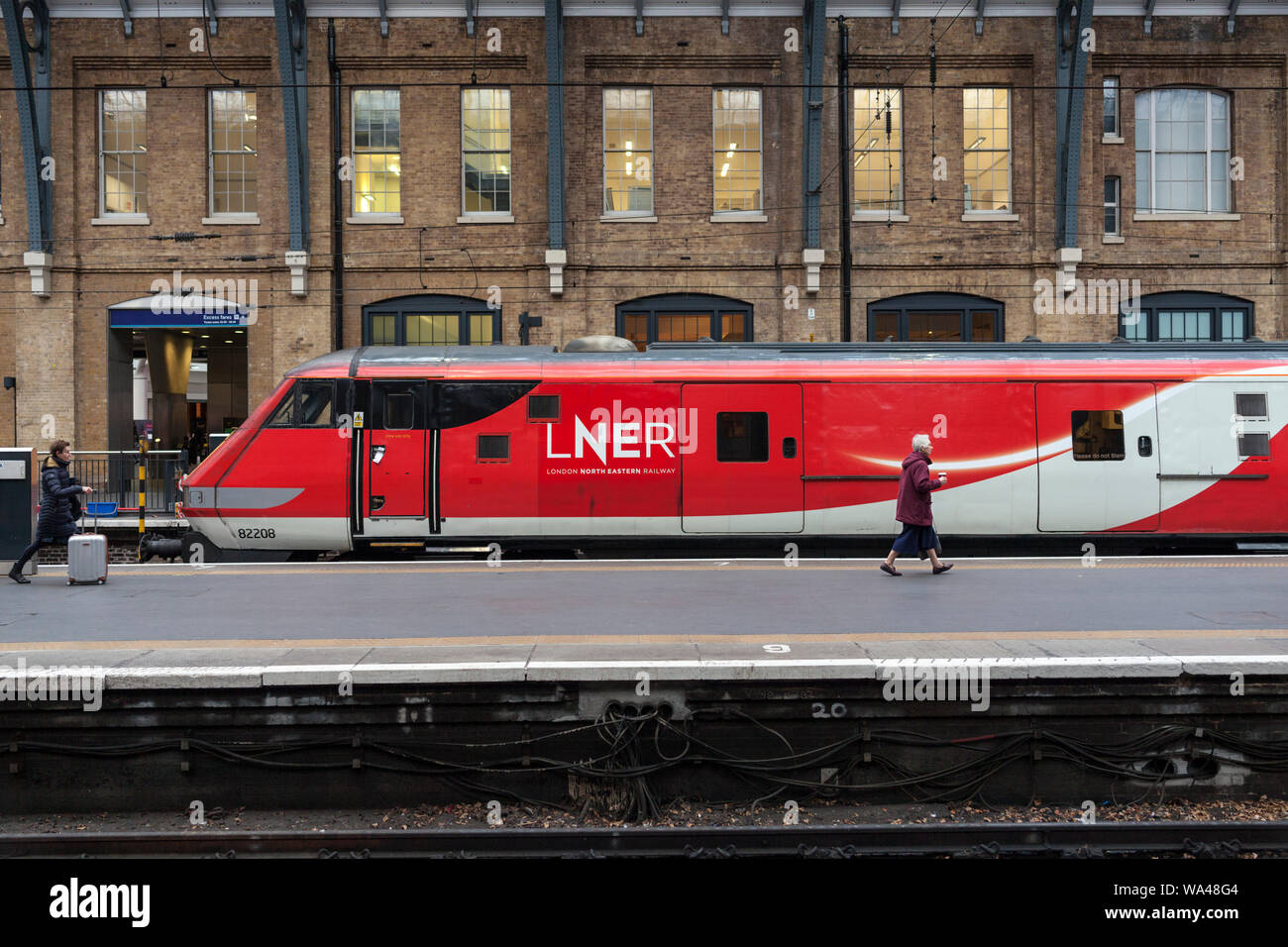 Passenger at London Kings Cross about to board a LNER train to Leeds passing a MK 4 DVT on the rear of a Intercity 225 Stock Photo
