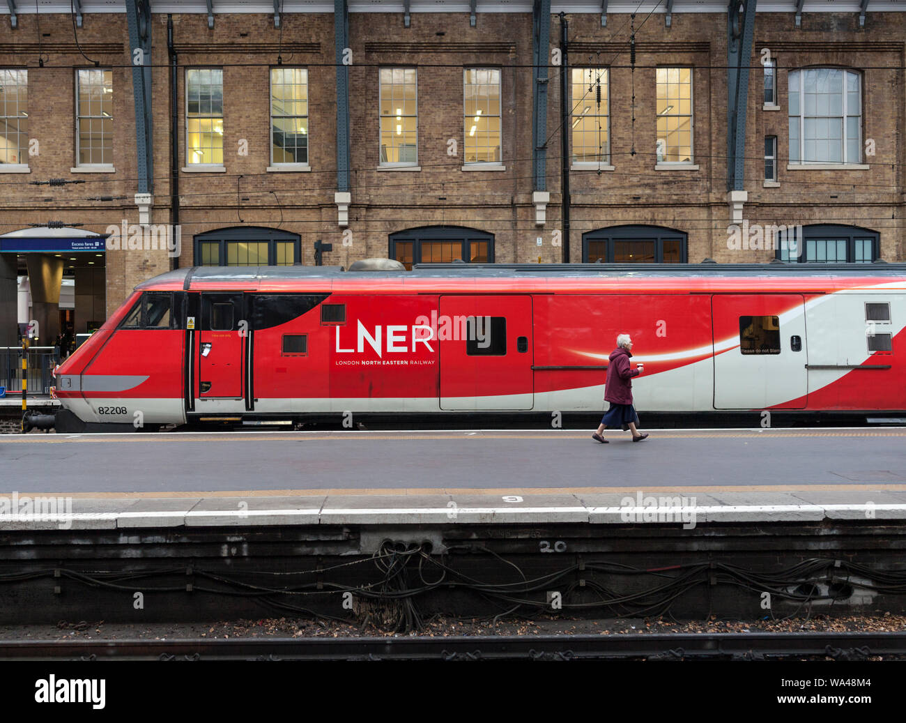 Passenger at London Kings Cross about to board a LNER train to Leeds passing a MK 4 DVT on the rear of a Intercity 225 Stock Photo