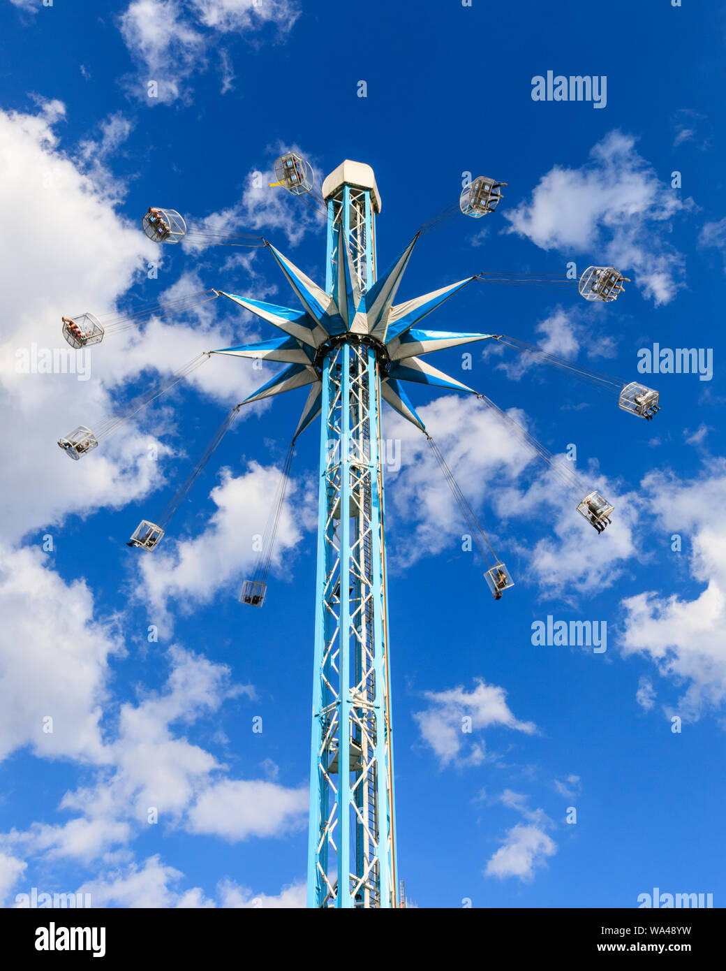 Southbank Starflyer fairground ride, tall funfair attraction, capsules swinging around central pillar against blue summer sky Stock Photo