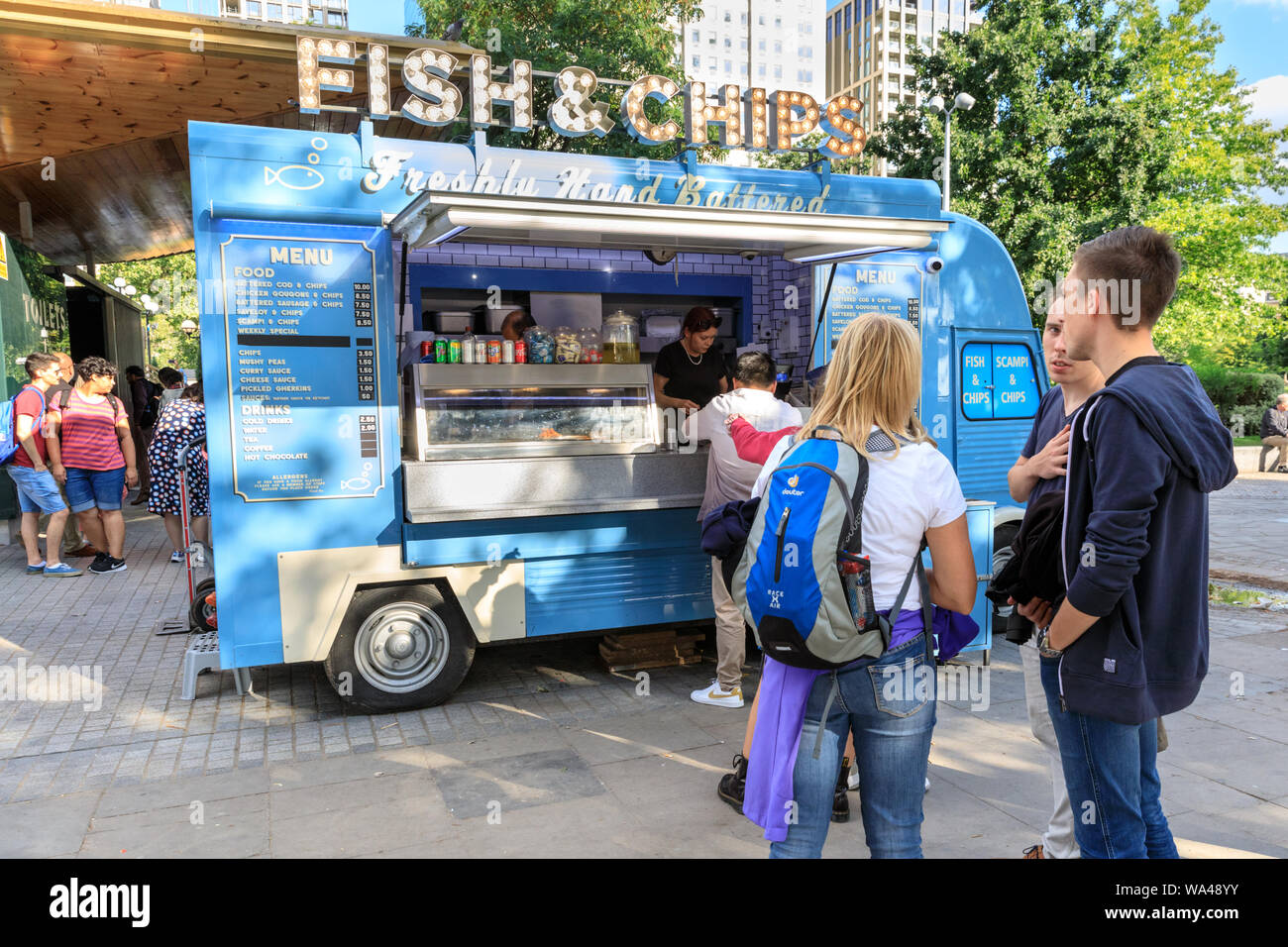 People queue outside a traditional British Fish & Chips takeaway van, fast food stall in London, UK Stock Photo