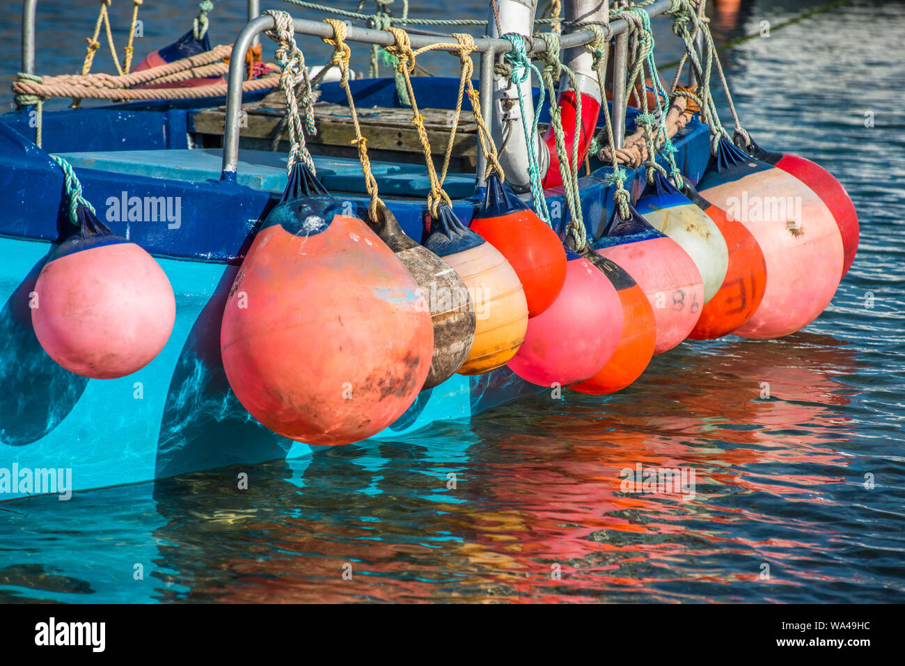 Colourful floats on fishing boat at Mousehole harbour Cornwall England