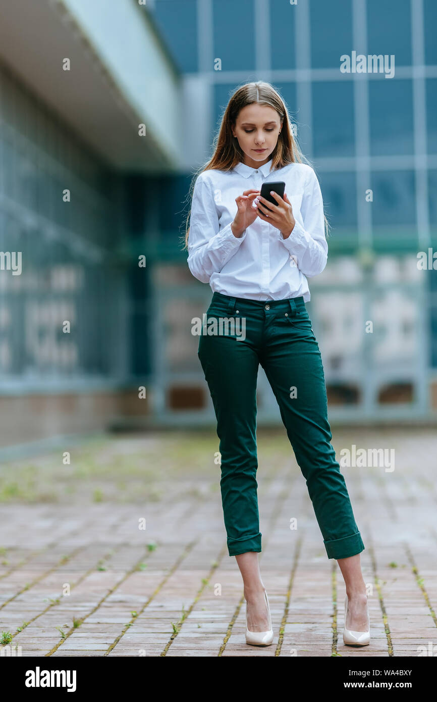 Business woman using phone. Successful female entrepreneur checking email on smartphone. Female texting message. Outdoor modern city urban life Stock Photo