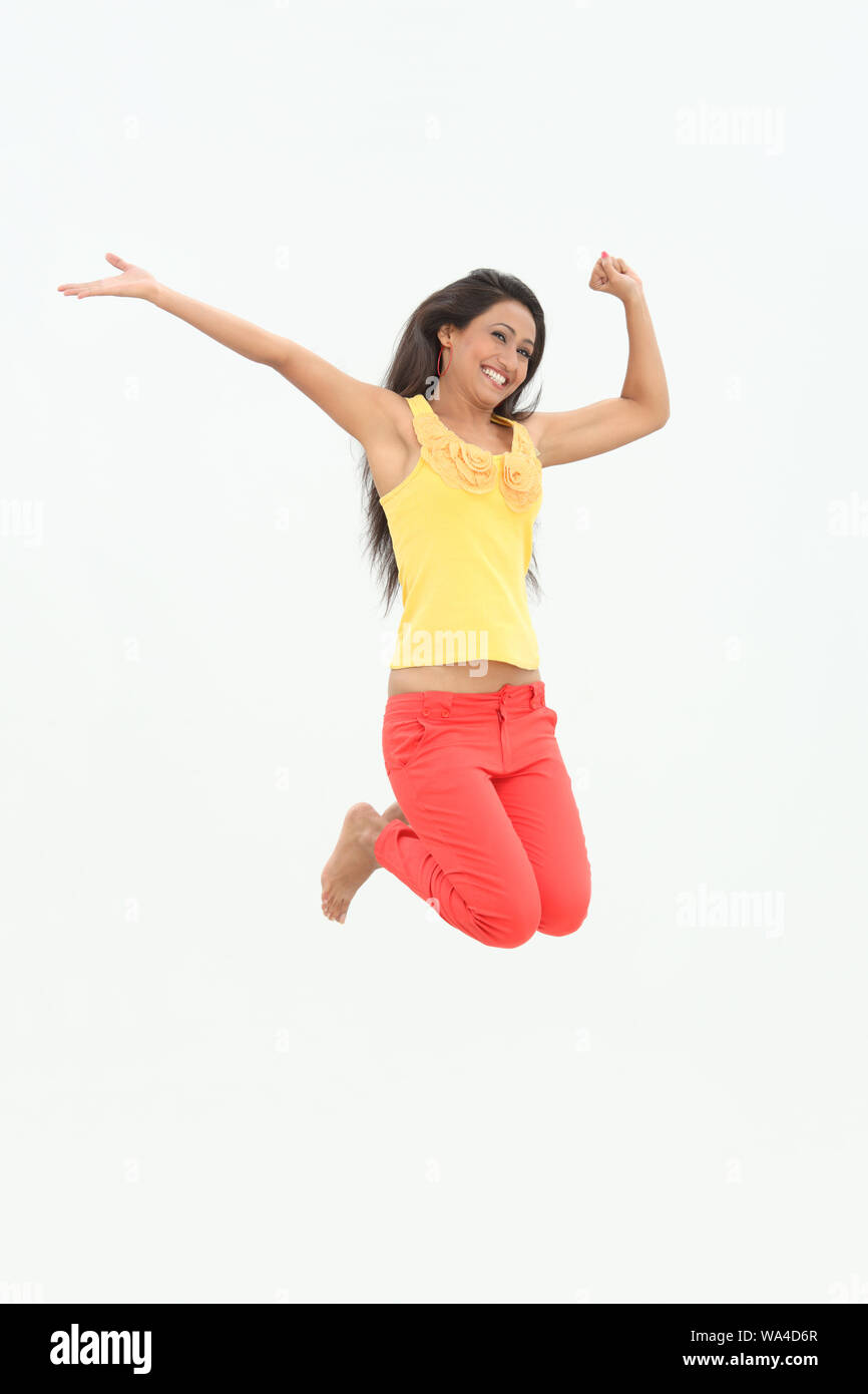 Young woman jumping in air and smiling Stock Photo - Alamy