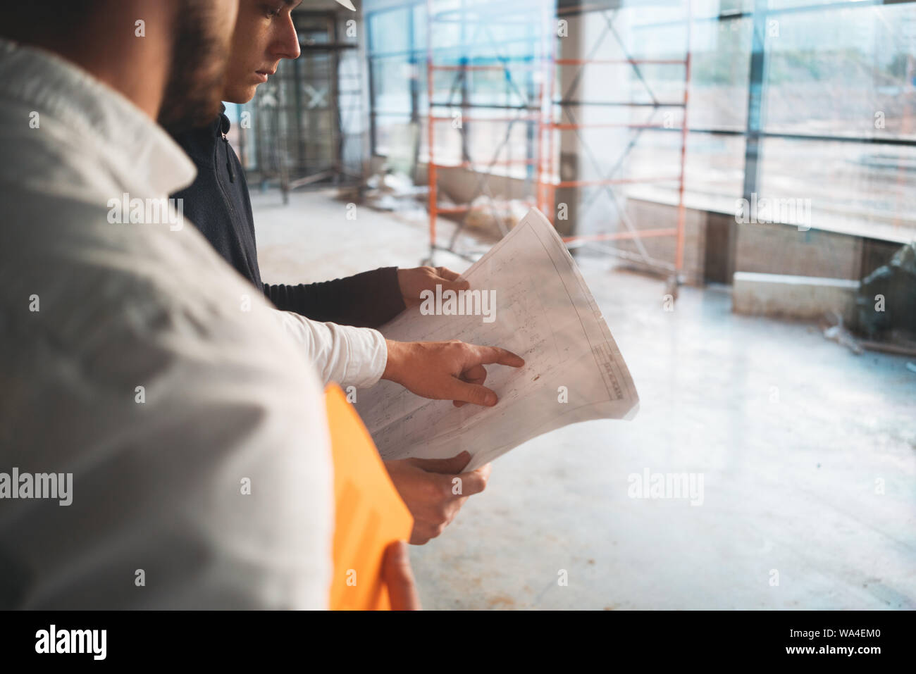 Two building engineers with blueprint working on construction site. Industrial enginer and