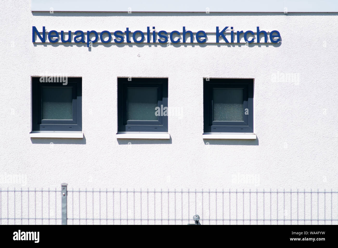 The white modern facade of a New Apostolic church with windows and fence. Stock Photo