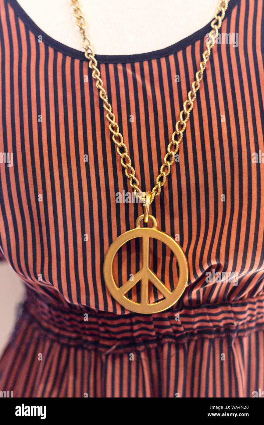 A giant peace sign necklace with a striped dress is a fun find at Zen and Now Pre-Loved Clothing in Asheville, NC, USA Stock Photo
