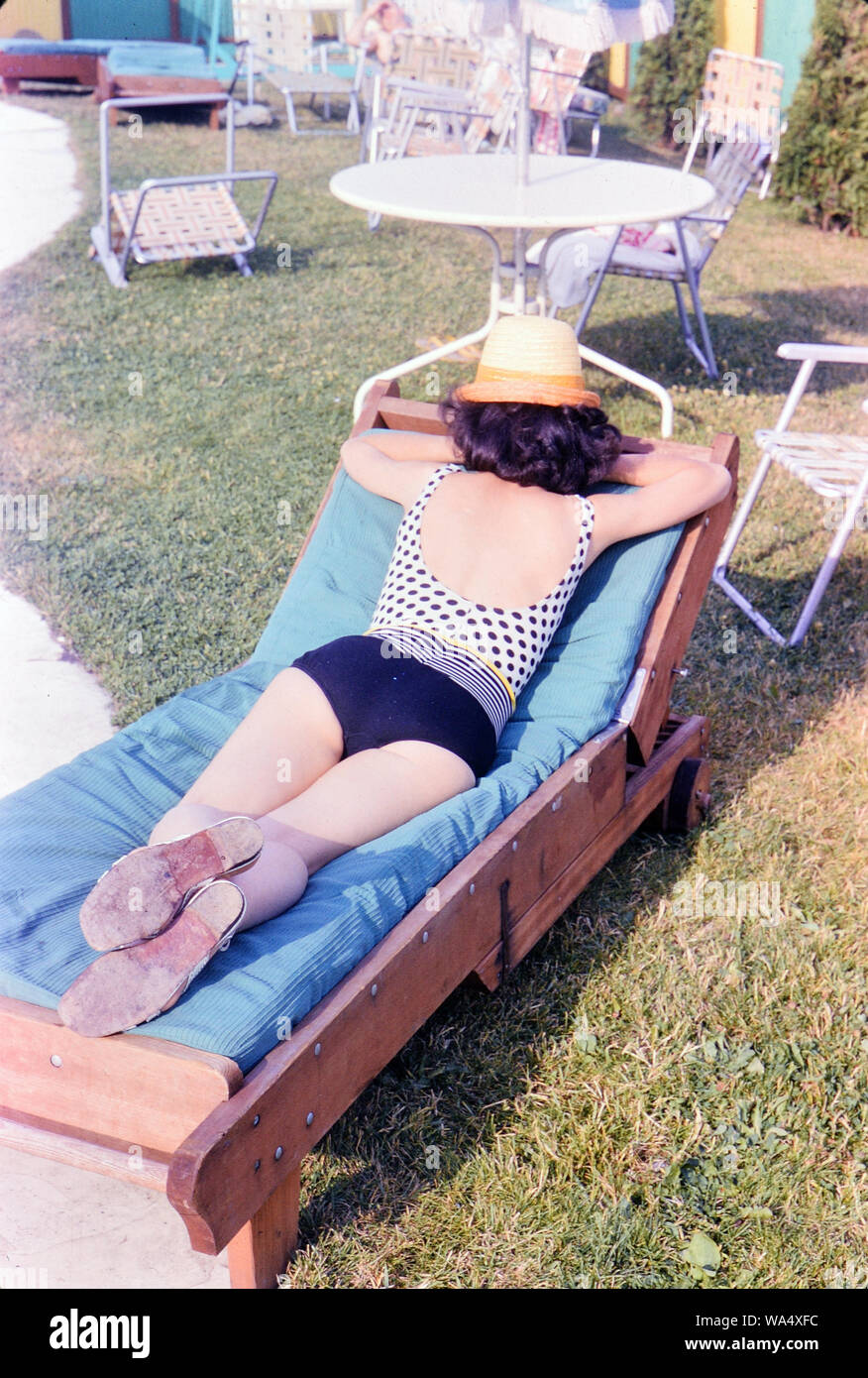 Woman sunbathing outdoors, lying on her stomach, wearing a hat 1966 Stock Photo