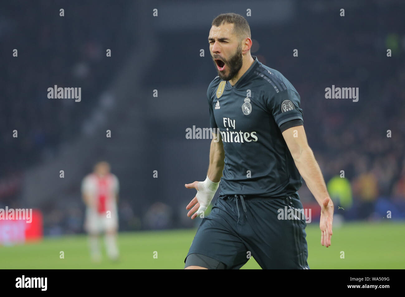 Real Madrid forward, Karim Benzema, celebrates the goal during a UEFA Champions League match playoff 1/8 finals game against Ajax Stock Photo