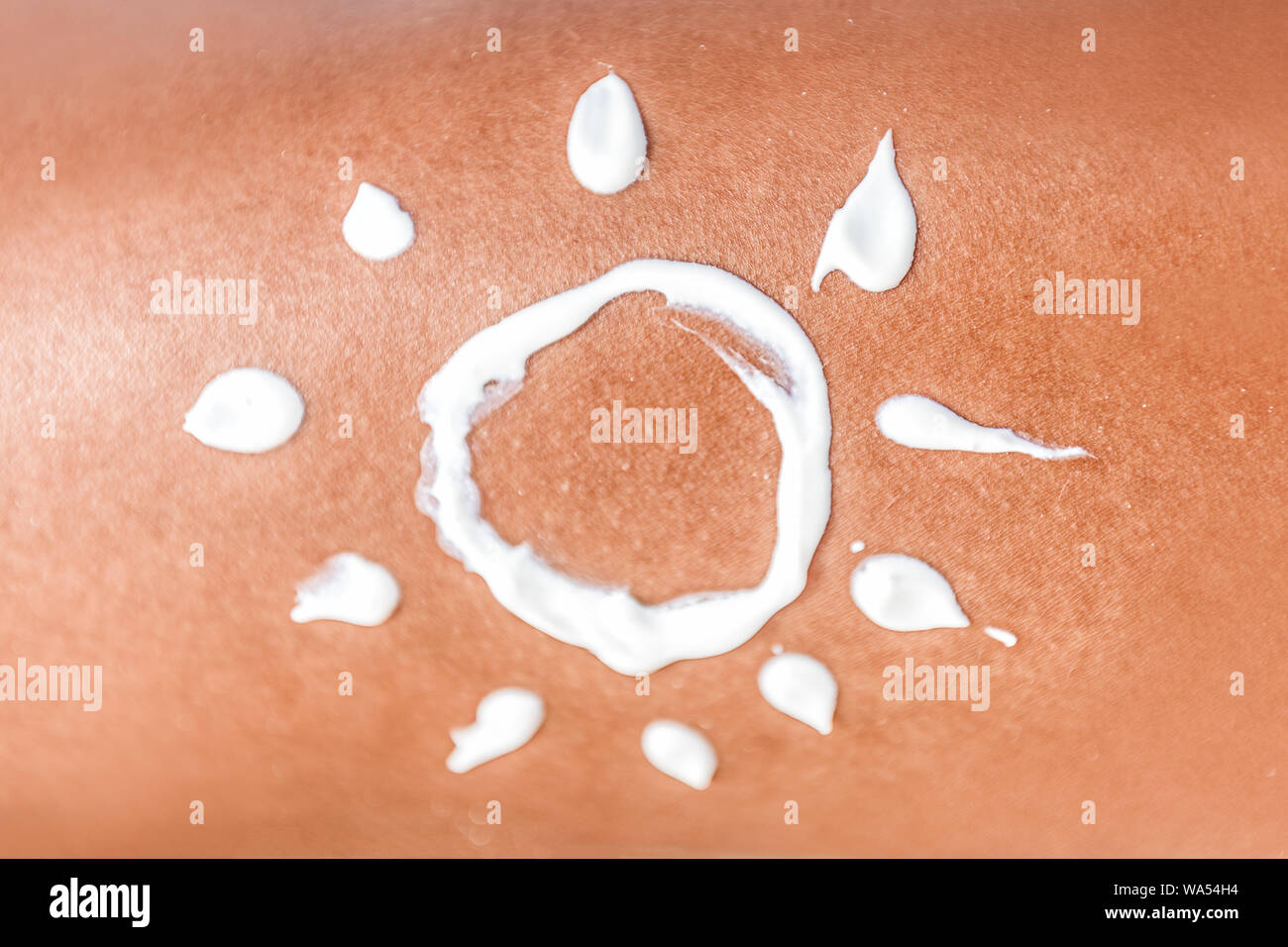 Sunscreen suntan lotion sun drawing in sunblock cream on tanned skin closeup. Female body crop of illustration painted on body Concept for skin cancer or sunburn uv rays protection. Stock Photo