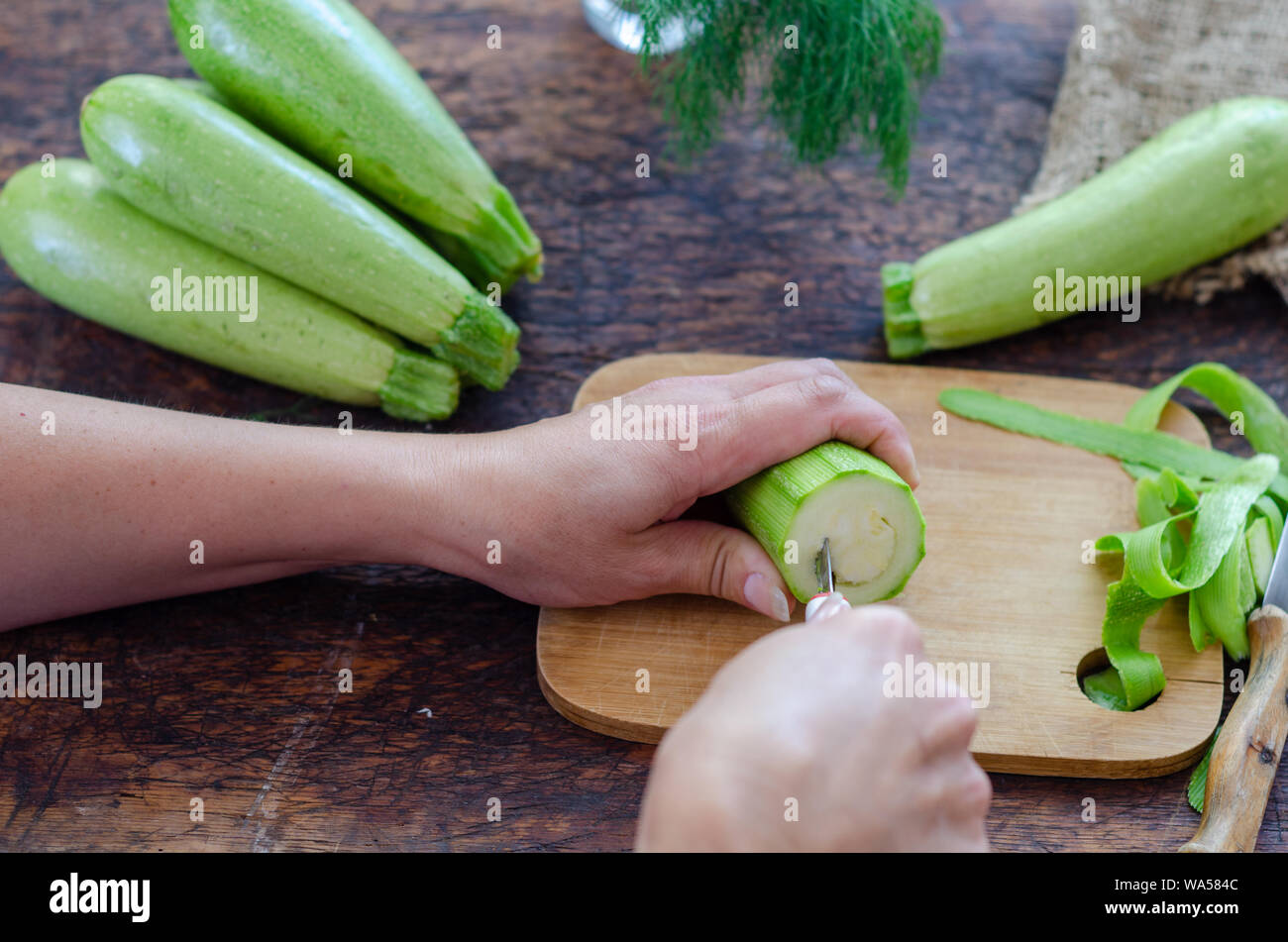 Woman is carving the zucchini in the kitchen. Stock Photo