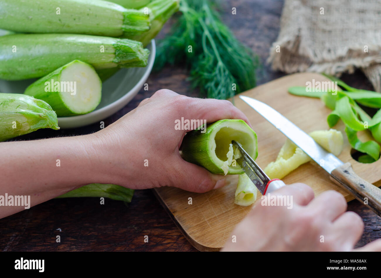 Woman is carving the zucchini in the kitchen. Stock Photo