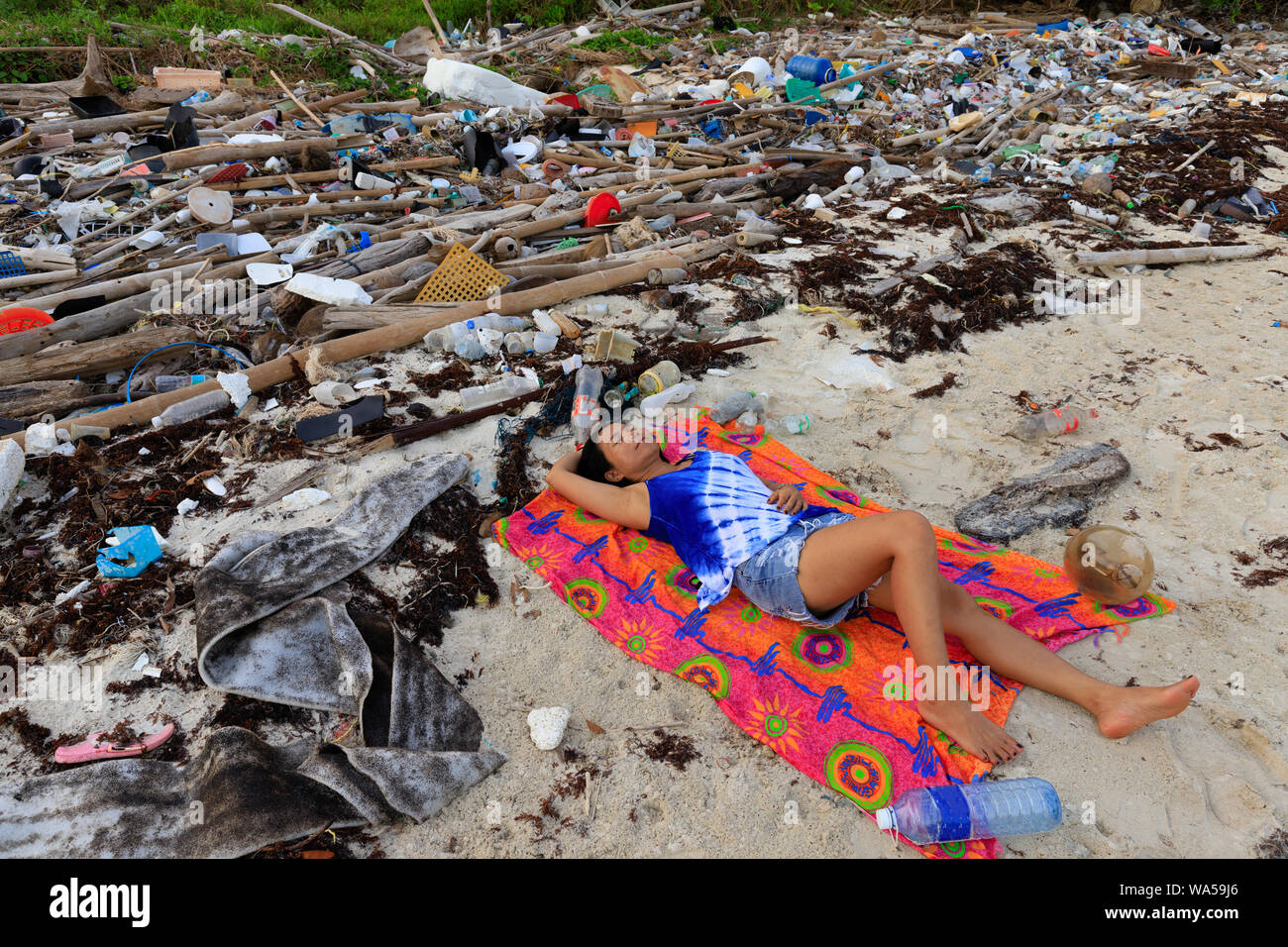 Woman lying on a beach with important plastic pollution in Thailand Stock Photo