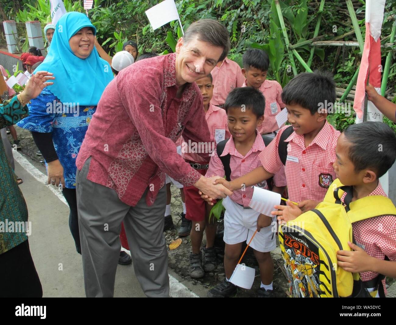 Direktur USAID Indonesia Andrew Sisson berjabat tangan dengan murid SD di desa Patemon. (17126926562). Stock Photo