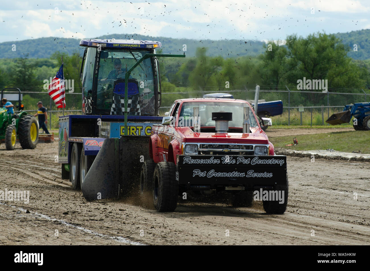 A powerful truck pulls a heavy weight and kicks up dirt during a truck