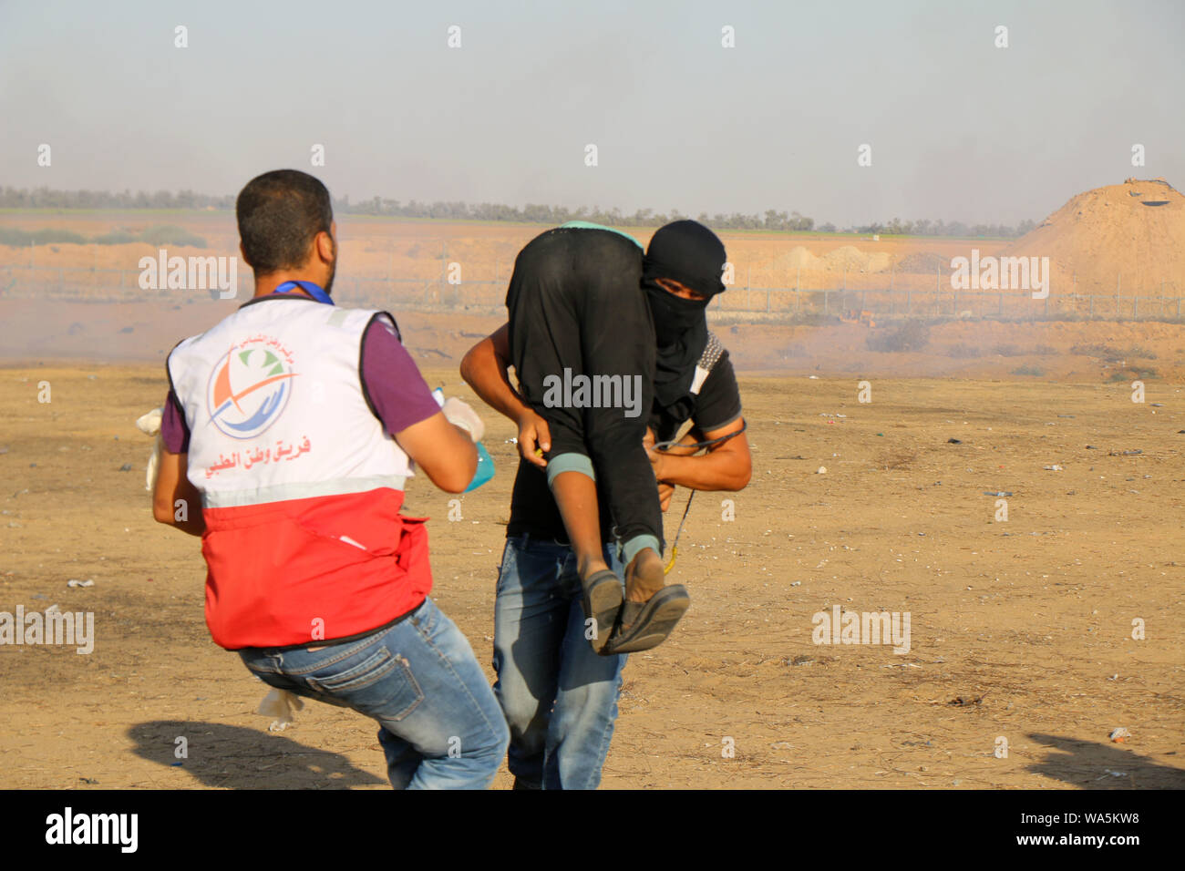 Khan Younis, Gaza Strip, Palestinian Territory. 16th Aug, 2019. A wounded Palestinian protester is evacuated during clashes with Israeli troops following the tents protest where Palestinians demand the right to return to their homeland at the Israel-Gaza border. Credit: Mariam Dagga/APA Images/ZUMA Wire/Alamy Live News Stock Photo