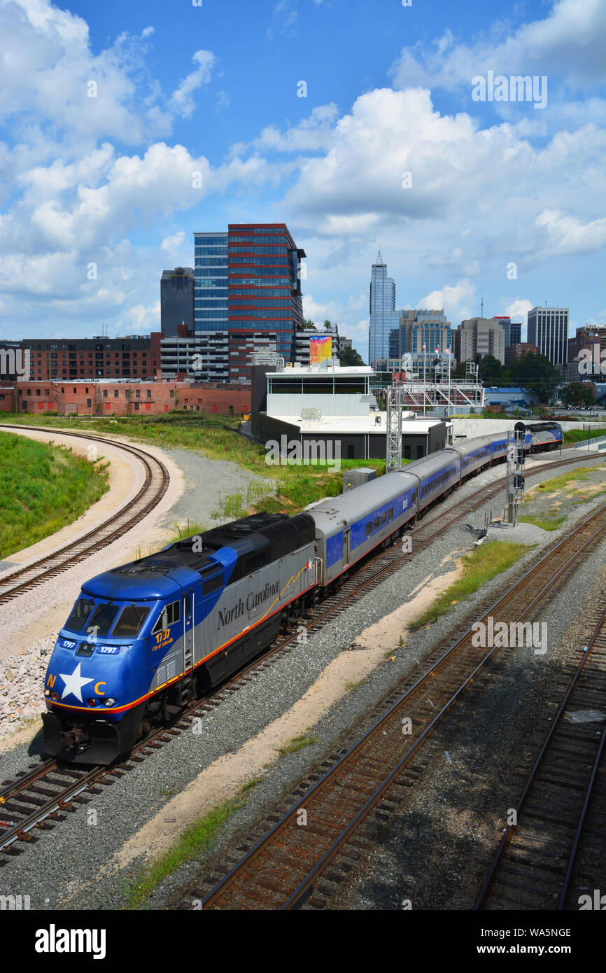 An Amtrak train leaves the Raleigh station with the skyline in the