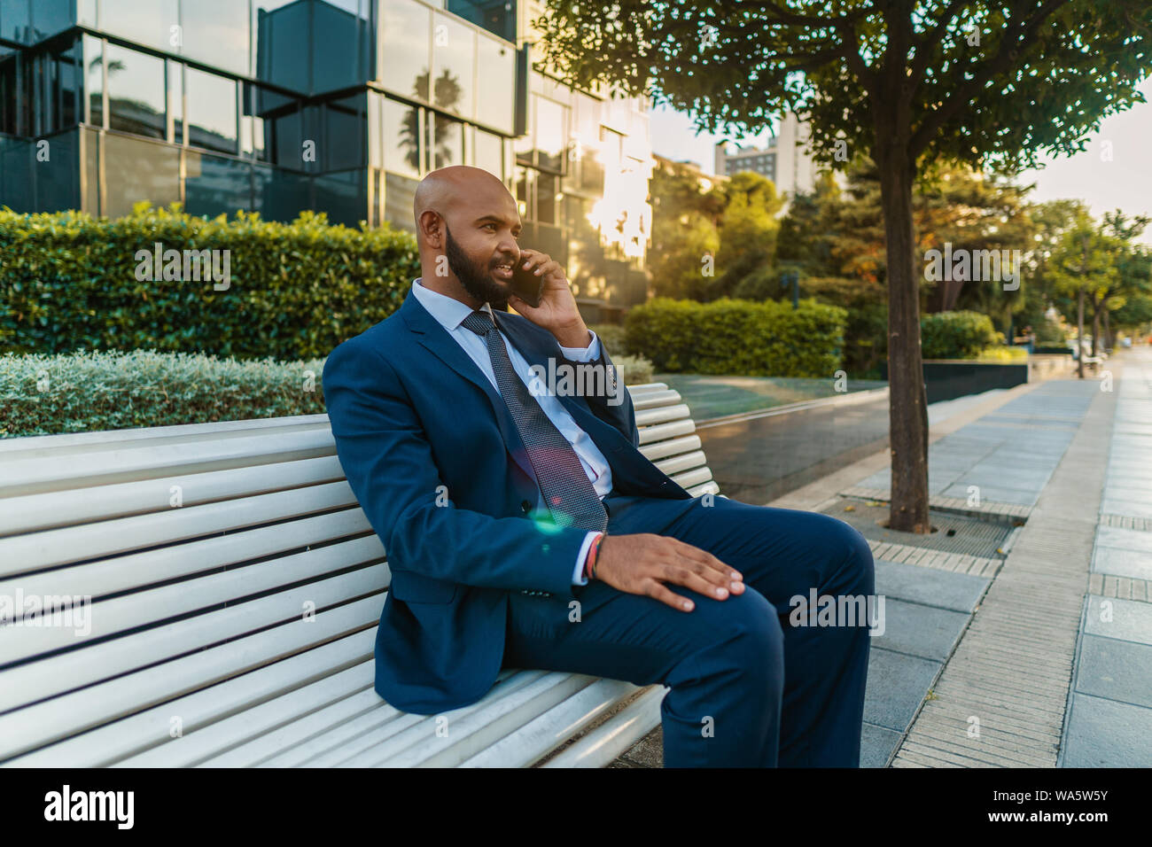 Indian businessman holding mobile phone wearing blue suit Stock Photo