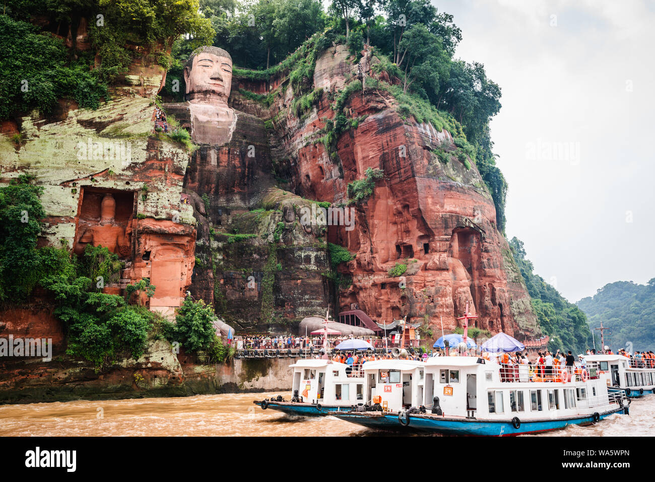 Leshan China, 5 August 2019 : View of the Leshan Giant Buddha and tourists boats on Min river in Leshan Sichuan China Stock Photo