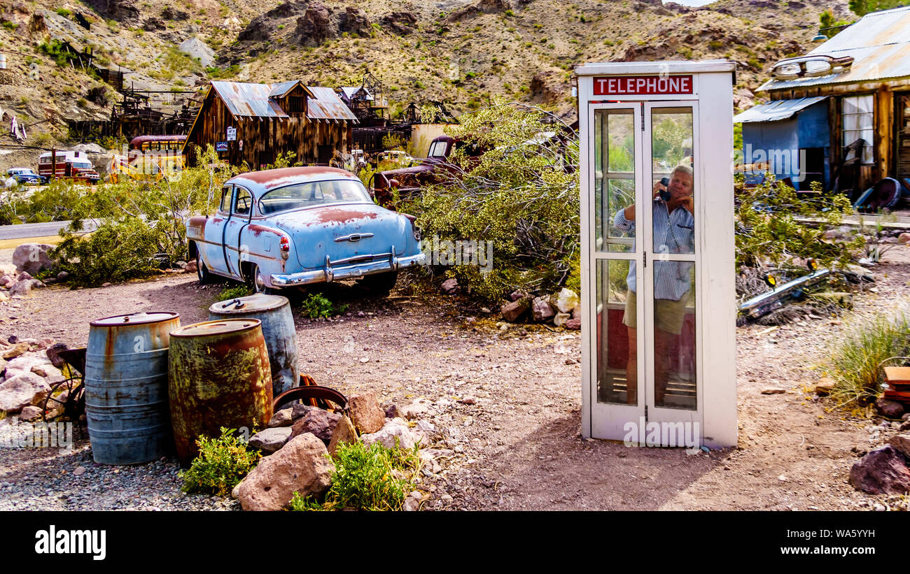 Vintage phone booth and vintage cars used in movies on display in the old mining town of El Dorado in the Eldorado Canyon in the Nevada Desert Stock Photo