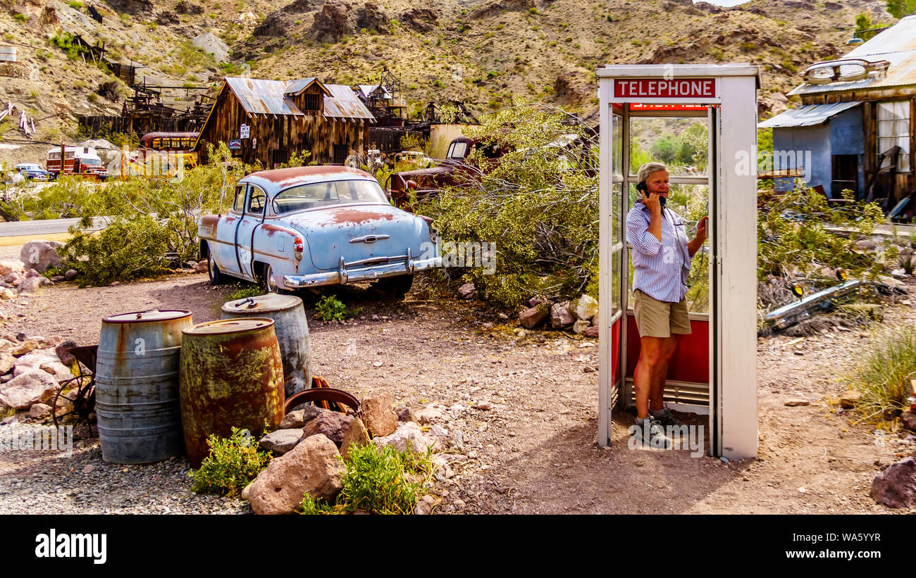 Vintage phone booth and vintage cars used in movies on display in the old mining town of El Dorado in the Eldorado Canyon in the Nevada Desert, USA Stock Photo
