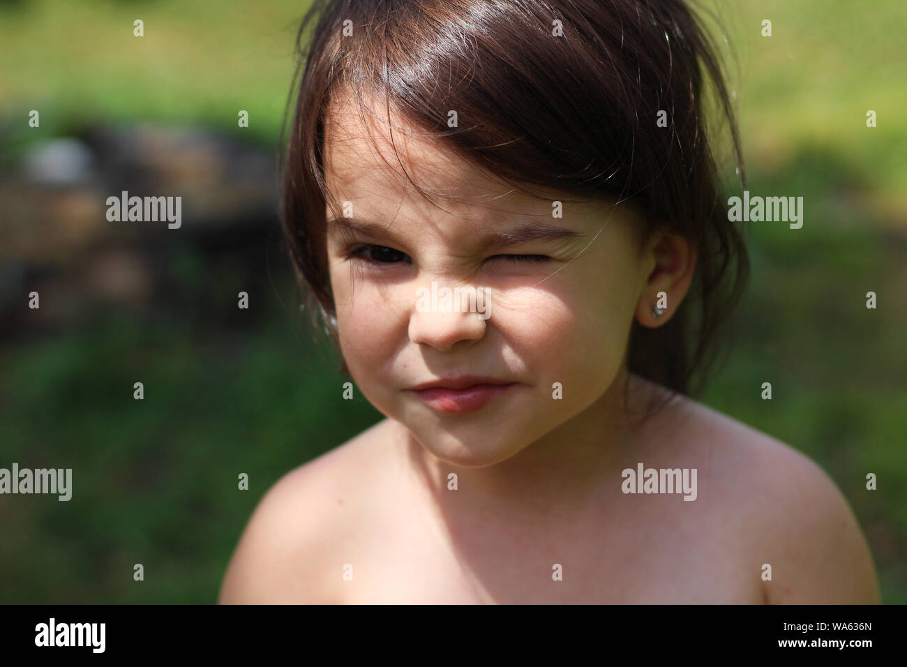 a little long-haired white girl without clothes stands in the middle of ...