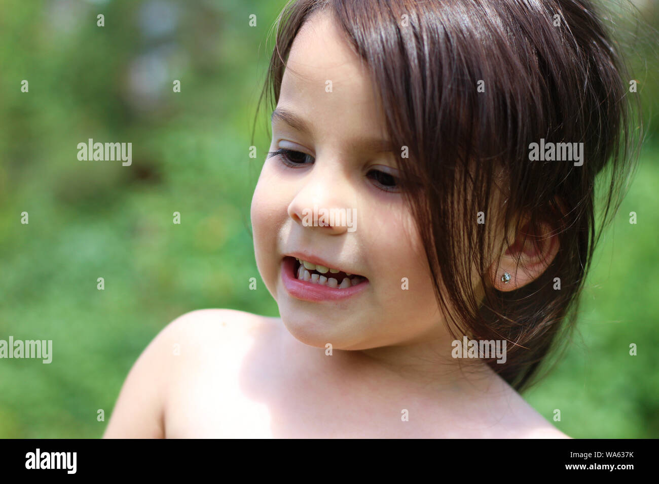 a little long-haired white girl without clothes stands in the middle of ...