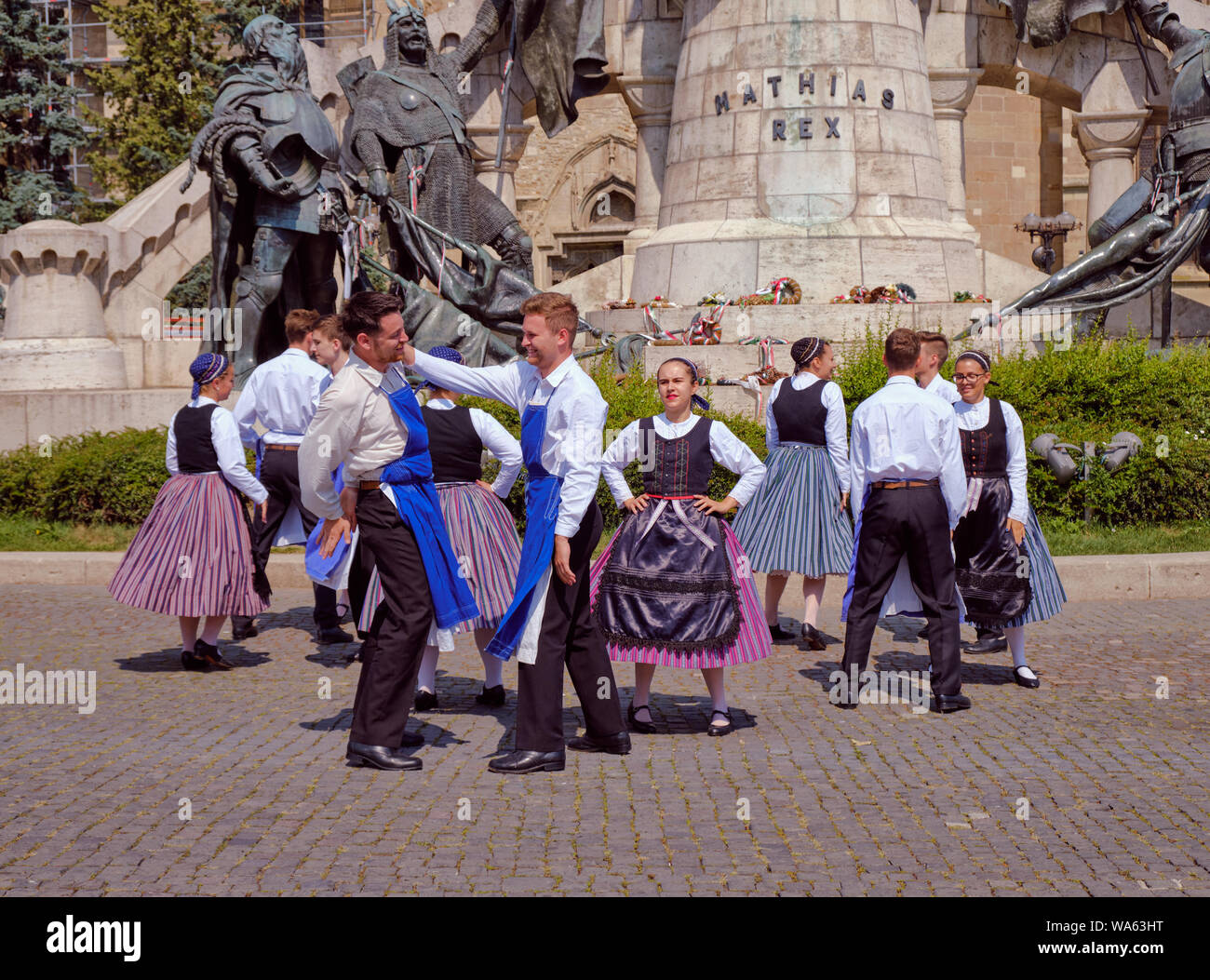 Hungarian Traditional dance in folkloric customs public performance in square. Males performing face slapping number under disapproving lady look Stock Photo