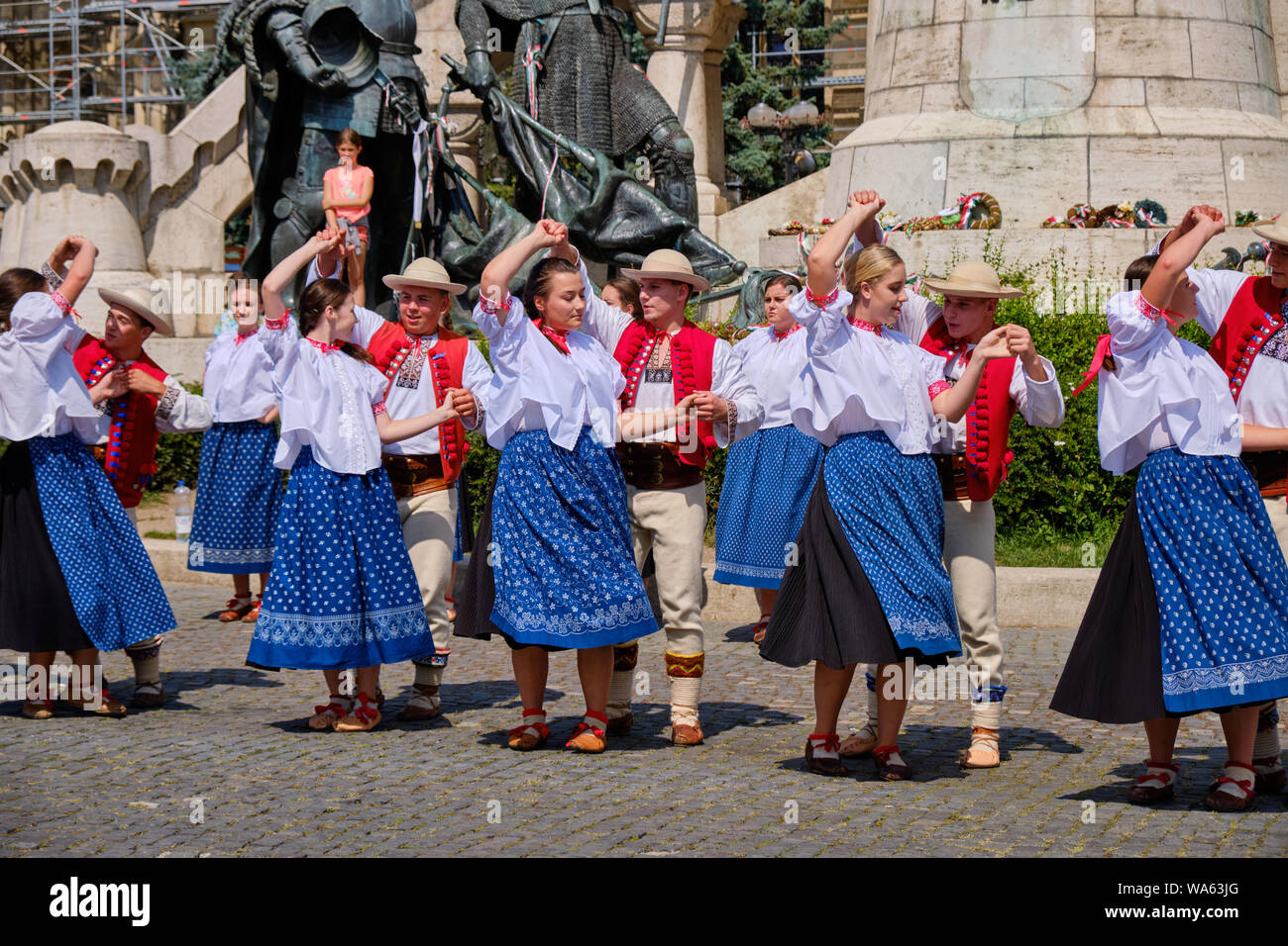 Polish Traditional dance troup in folkloric customs with a public performance in square. Dancers in line, with males twirling ladies under arms. Stock Photo