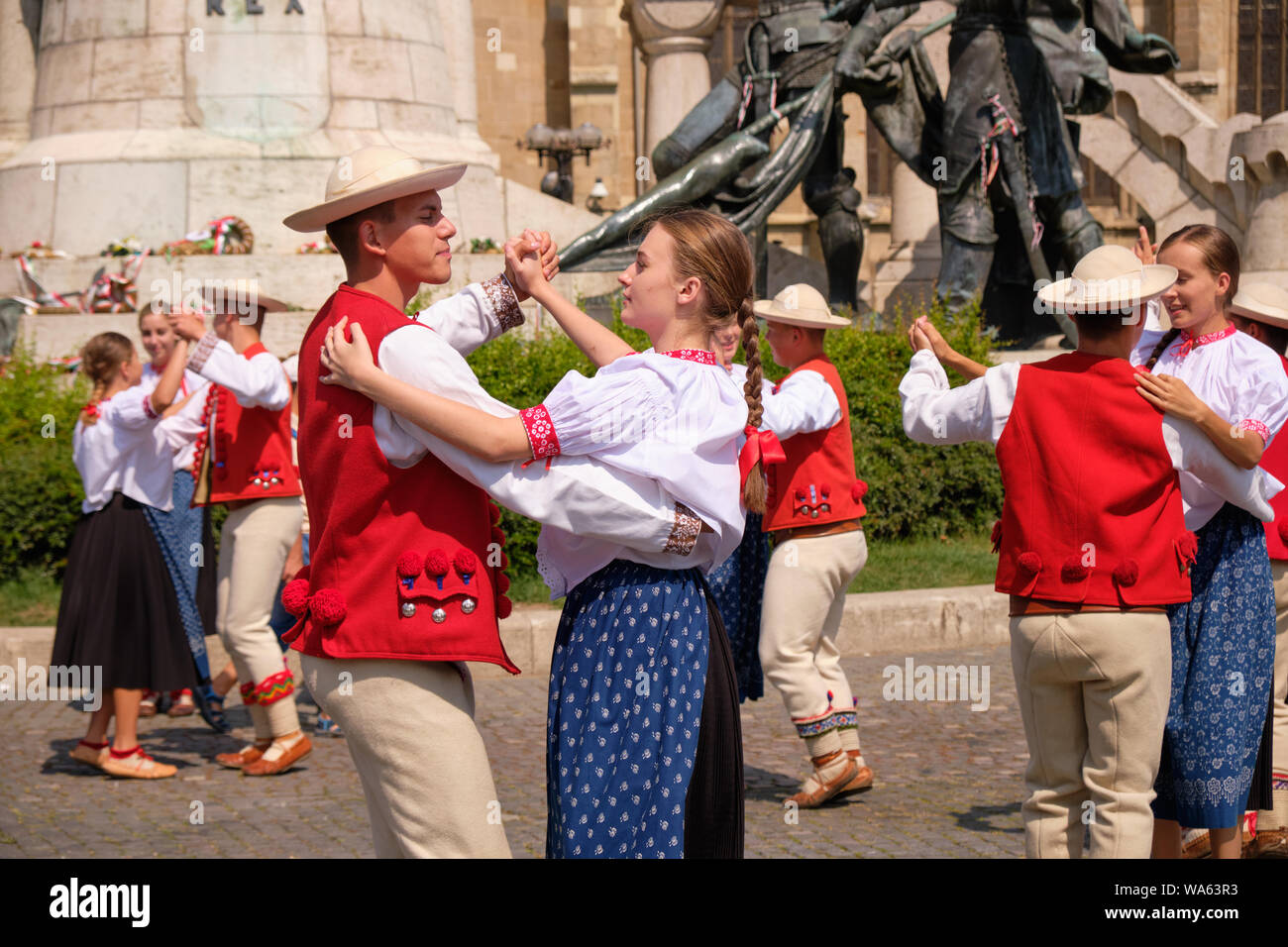 Polish Traditional dance troop in folkloric customs with a public performance in square. Couples dancing holding each other, focus on one pair. Stock Photo