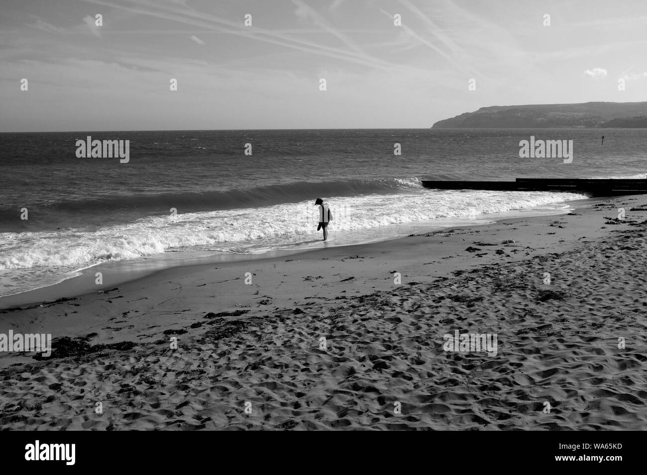 Standing alone at the water's edge on Yaverland Beach, Isle of Wight paddling in the gentle surf Stock Photo