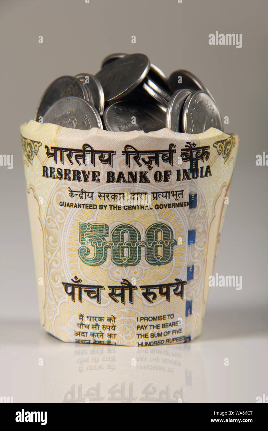 Five hundred rupee banknote cup full of coins Stock Photo