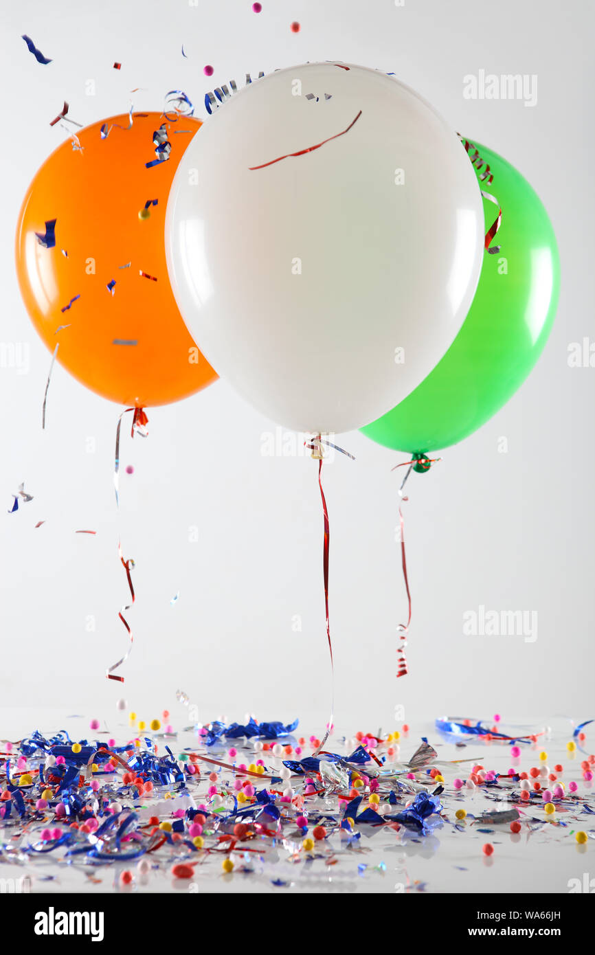 Tricolor balloons floating over confetti on a table Stock Photo