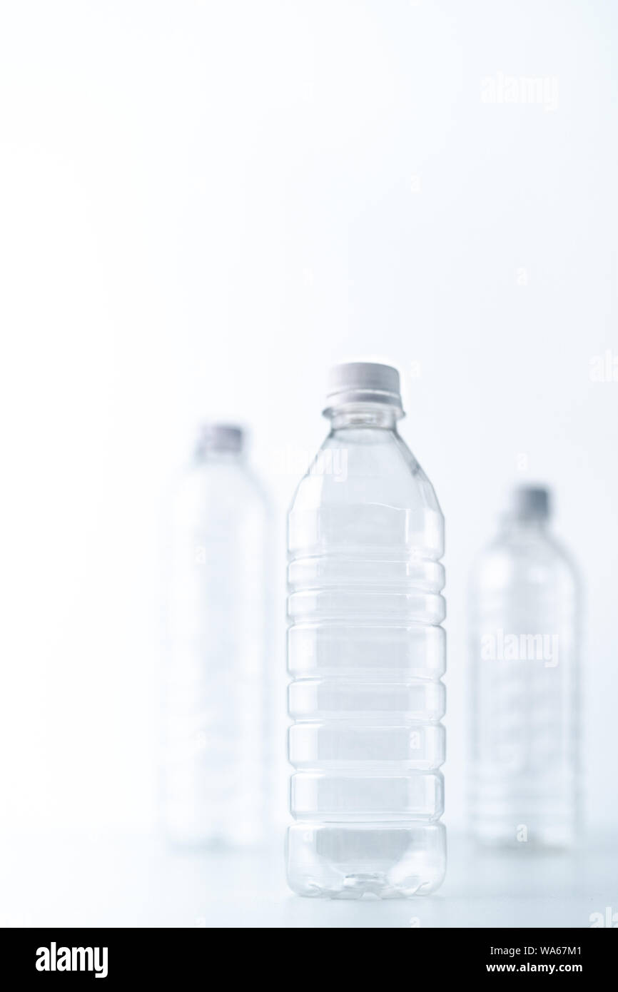 Plastic bottles in various shapes and sizes on white table and background, monotone, health and environment concept Stock Photo