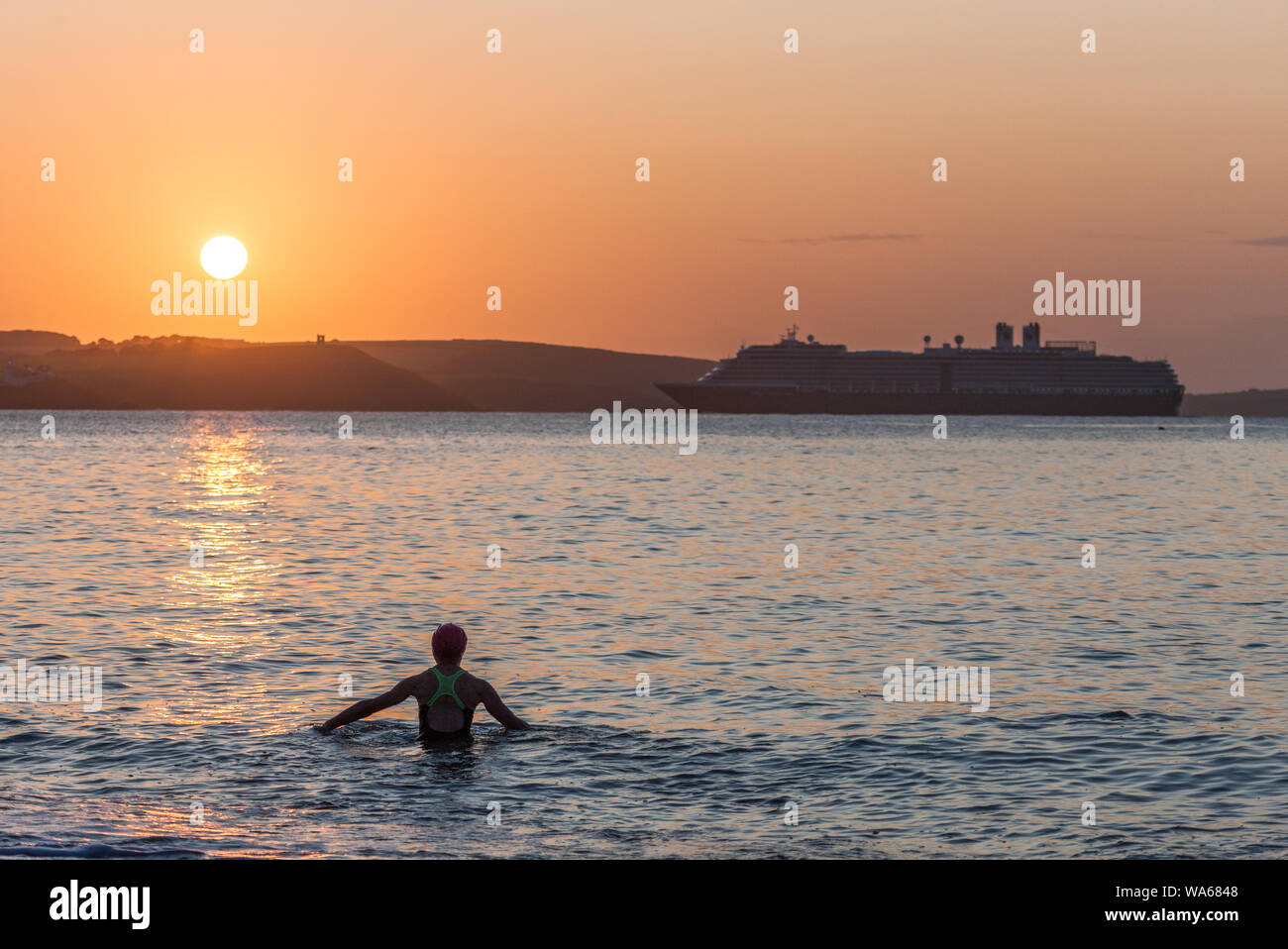 Myrtleville, Cork, Ireland. 18th August, 2019. Ursula Murphy from Douglas pauses from her morning swim to view the arrival of the cruise ship Zuiderdam at Sunrise in Myrtleville, Co. Cork, Ireland.  Credit;  David Creedon / Alamy Live News Stock Photo