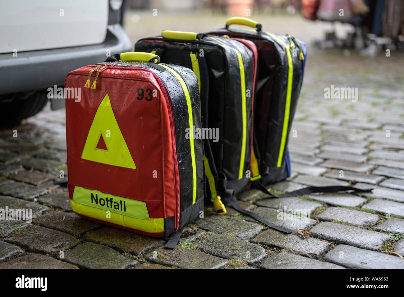 emergency cases of the mobile ambulance on cobblestone pavement in the rain at a large event in the city, selected focus Stock Photo
