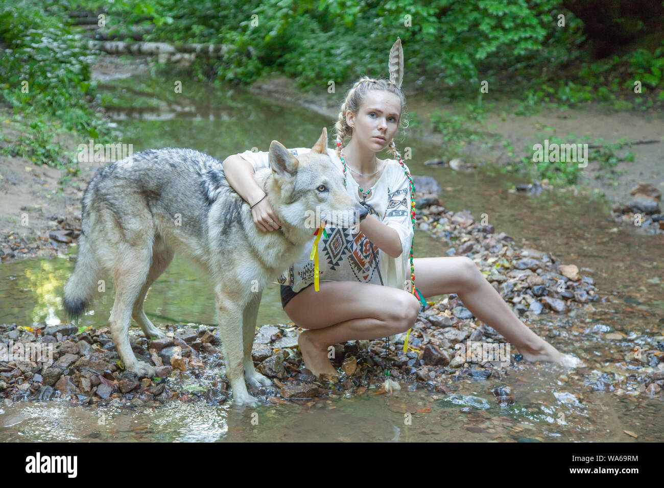 slim ethnic girl with her wolf dog in the deep forest alone Stock Photo