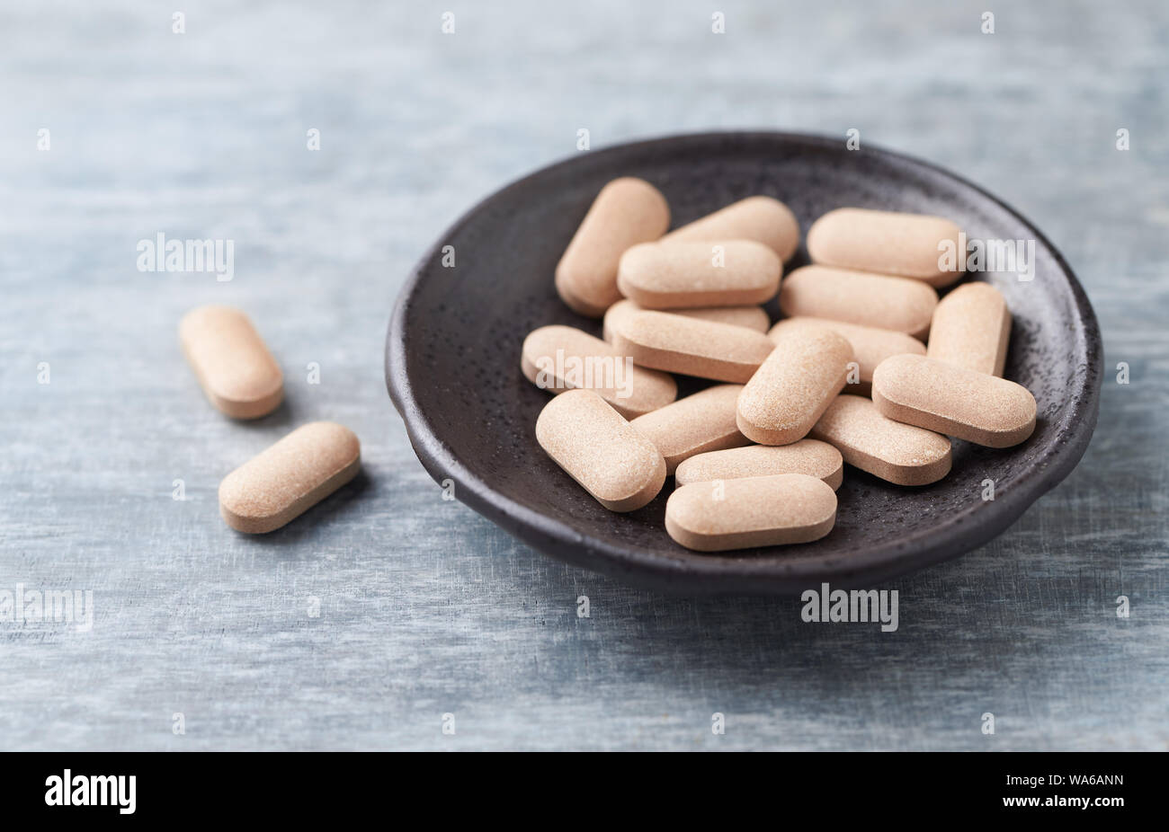 Rhodiola rosea. Golden root, rose root. Herbal pills with healthy medical plant. Healthy supplement on wooden background. Close up. Stock Photo