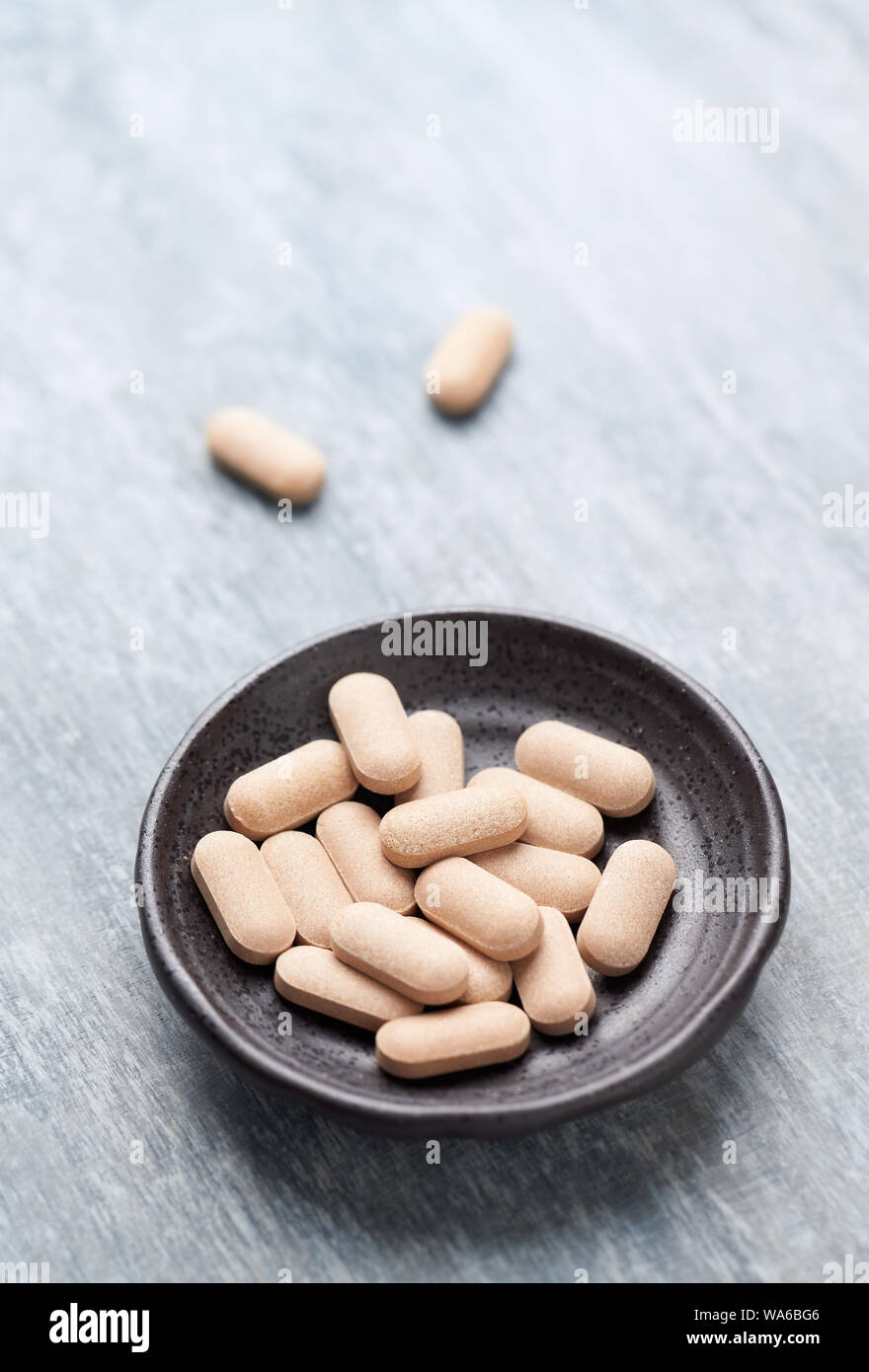 Rhodiola rosea. Golden root, rose root. Herbal pills with healthy medical plant. Healthy supplement on wooden background. Close up. Stock Photo