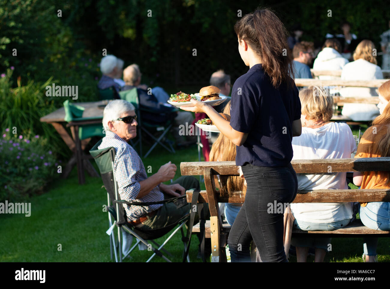 Waitress serving food during a garden production of A Midsummer Night's Dream Stock Photo