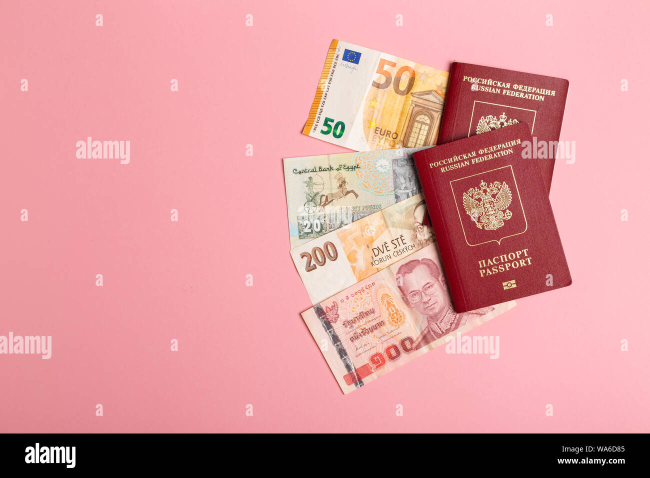 Two Russian passports over bankotes of different regions and countries on pink background Stock Photo