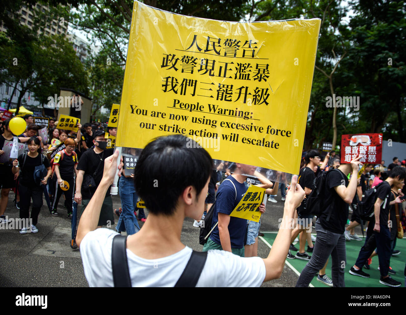 Hong Kong, China. 18th August 2019. A protest rally participant comes to Victoria Park with a sign saying 'People Warning: You are now using excessive force our strike action will escalate'. Photo: Gregor Fischer/dpa Credit: dpa picture alliance/Alamy Live News Stock Photo