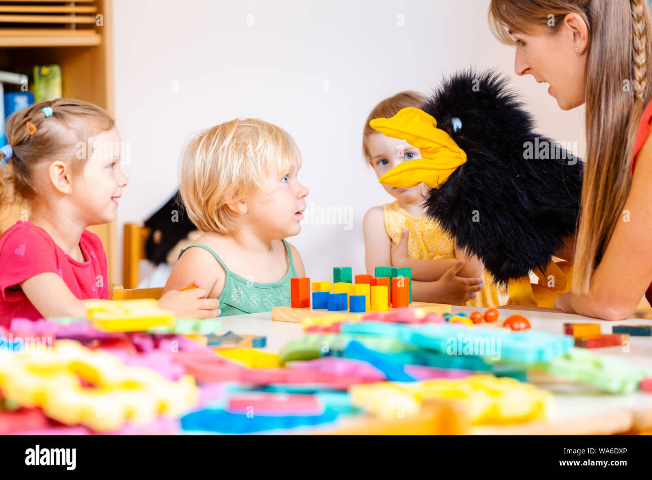 Kindergarten teacher and children playing with hand puppet Stock Photo