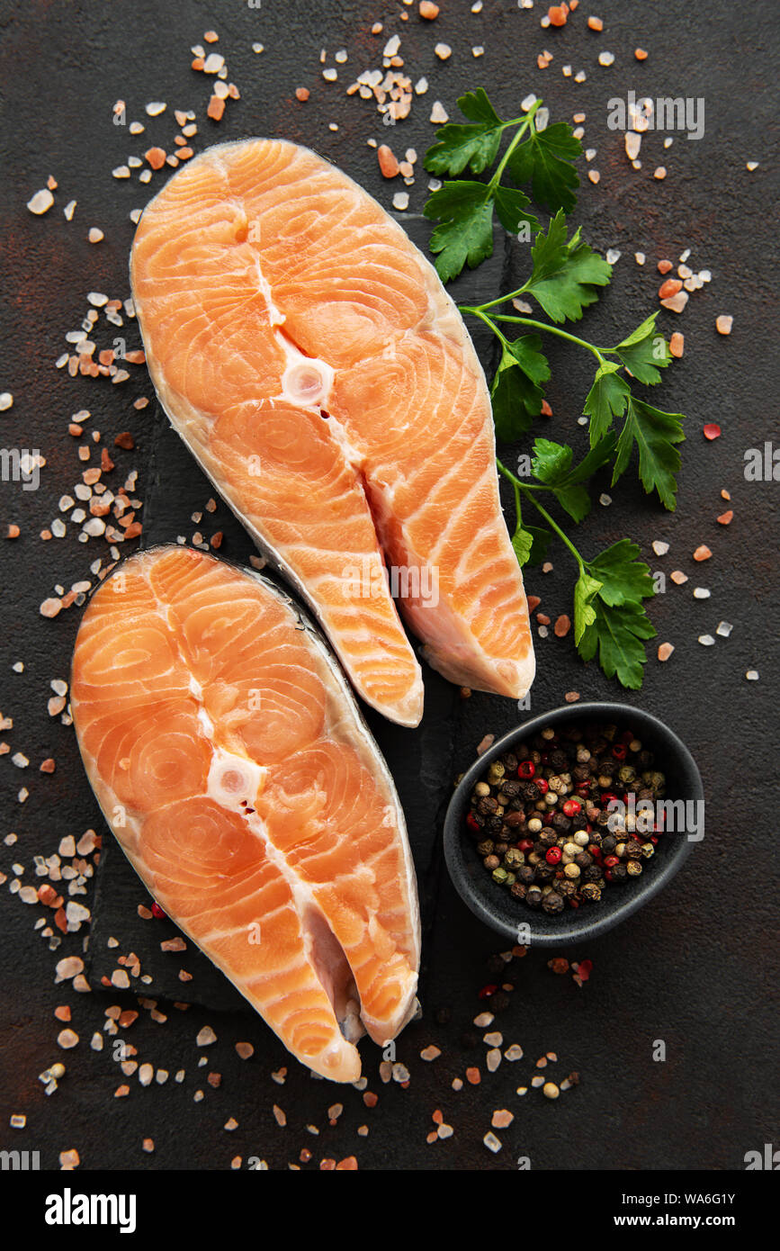 Raw salmon steaks and ingredients on a black slate board Stock Photo ...