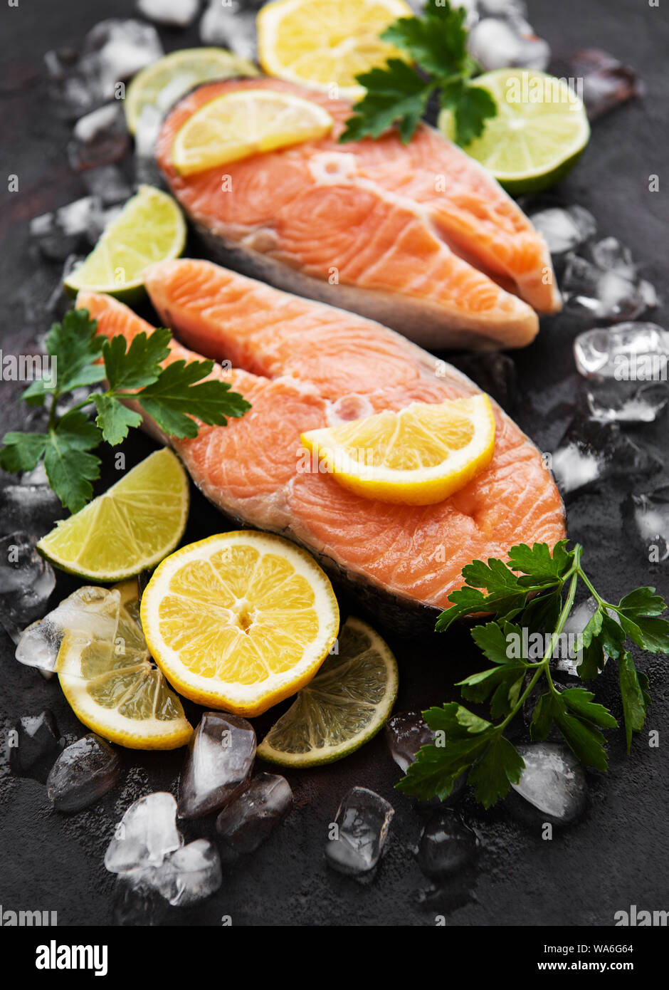 Raw salmon steaks and ingredients on a black slate board Stock Photo ...