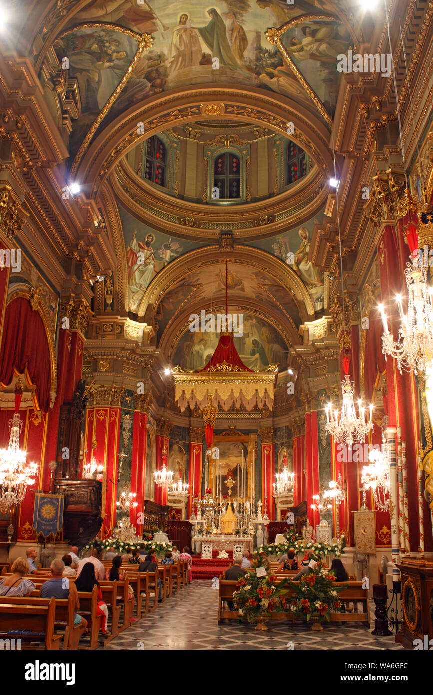 The baroque interior of the Roman Catholic parish church at Msida, Malta, decorated with flowers and tapestries for the annual feast of St Joseph. Stock Photo