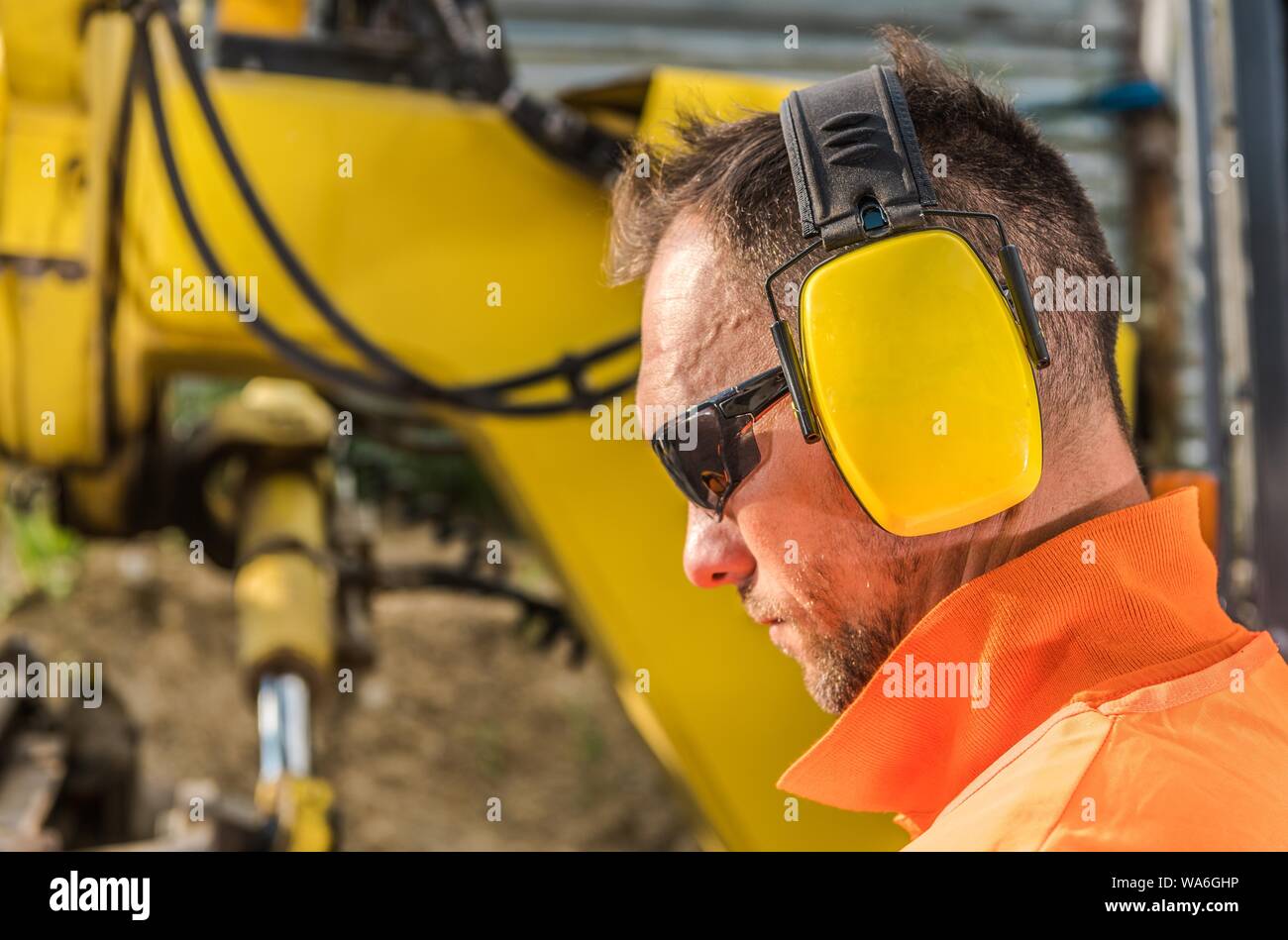 Noise Reduction Hearing Protection Headset. Caucasian Construction Contractor Wearing Sunglasses and Headphones. Stock Photo
