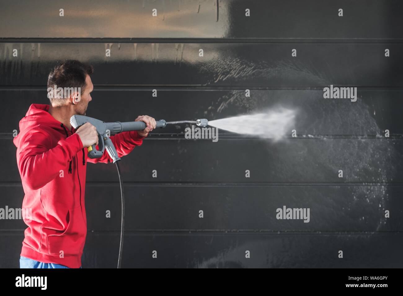 Pressure Washing Garage Gate. Men with Powerful Washer Cleaning Garage